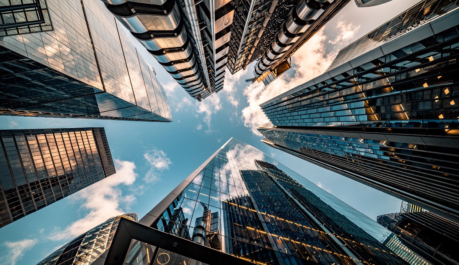 looking straight up at the tops of city skyscrapers from the ground
